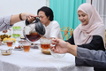 Asian muslim people pouring water, having dinner together at home - PhotoDune Item for Sale