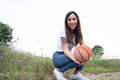 Young mother crouching with a basketball ball outdoors - PhotoDune Item for Sale