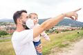 Dad with mask pointing ahead while holding a little girl - PhotoDune Item for Sale
