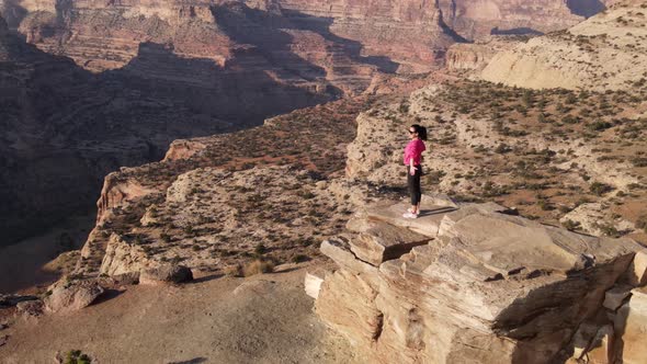 Aerial woman hiking on the edge of the San Rafael River Canyon in Utah