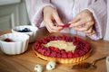 Close up of woman's hands decorating raspberry tart, cooks delicious pie with fresh berries - PhotoDune Item for Sale