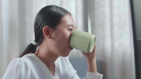 Asian Woman Engineer With The House Model Drinking Coffee While Working On A Desktop At Home