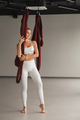 A portrait of a girl in white sportswear stands near a hanging Yoga hammock in the fitness room - PhotoDune Item for Sale