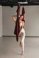 Portrait of a girl in white sportswear sitting in a hanging yoga hammock in the fitness room - PhotoDune Item for Sale