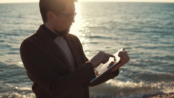 Adult Man Working on a Portable Tablet, Businessman Standing By the Sea