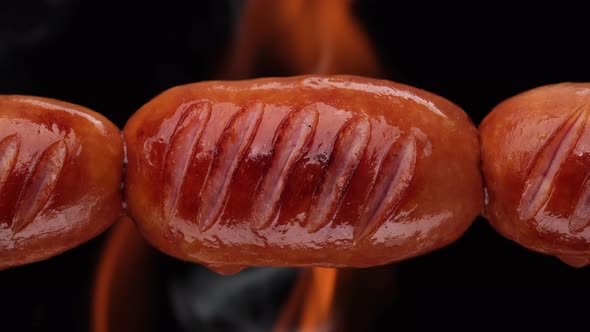 Fry sausages on open fire. Grilled sausages with Flame fire on background, sliding shot