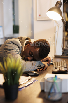 ping at work on desk because of extreme fatigue. Exhausted businessman suffering from sleepiness after working late at night at company project