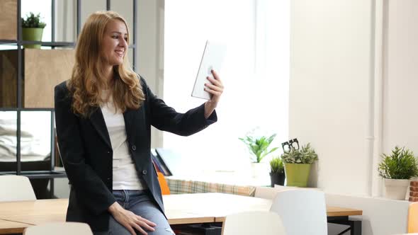 Video Chat on Tablet by Businesswoman Sitting on Desk