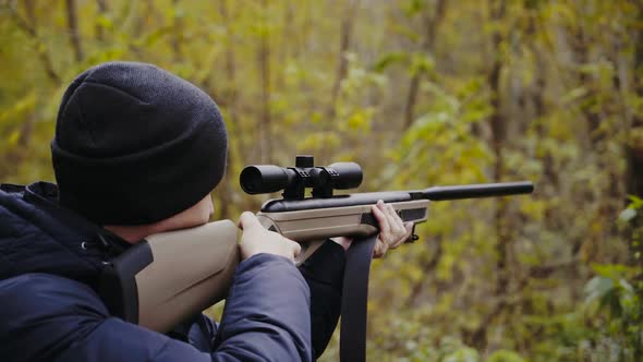 Man aiming with hunting rifle. Hunter man looking through the scope of hunting rifle