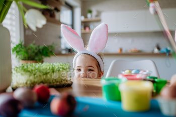 Little girl with bunny ears enjoying easter time in home.