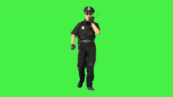 Caucasian Policeman Walks Sending a Message with Radio on a Green Screen Chroma Key