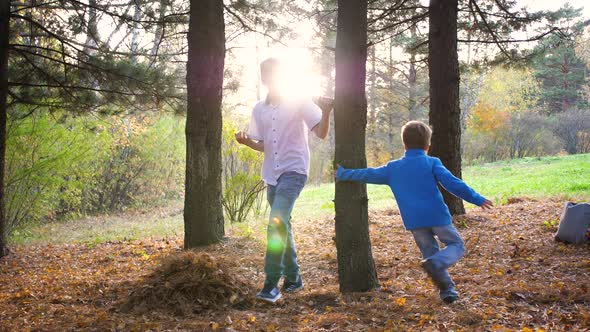 A Teenager Plays with a Child Runs in the Park Around a Tree and Catches Up with Him