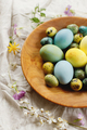 Rustic easter still life. Stylish easter eggs and blooming spring flowers in wooden bowl - PhotoDune Item for Sale