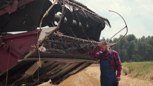 Tired Harvester Farmer Near the Reaper with a Reel of Agricultural Machinery