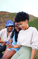 Young woman looking at her phone together with her two friends on a mountain with vegetation - PhotoDune Item for Sale
