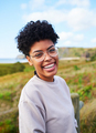 African American woman with glasses laughing over a nature landscape in the background - PhotoDune Item for Sale