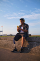  man with a prosthetic leg sitting near beach promenade listening music with wireless headphones  - PhotoDune Item for Sale