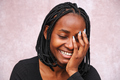 Portrait on a brown background of Afro woman laughing, eyes closed and one hand on her face. - PhotoDune Item for Sale