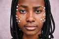 Frontal view of afro woman looking at camera with adhesive pearls on her face. - PhotoDune Item for Sale