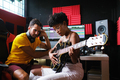 Afro woman sitting next to the sound engineer, playing the guitar. - PhotoDune Item for Sale