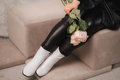 Close-up of legs and a bouquet of flowers of a stylish woman in black leather clothes sitting - PhotoDune Item for Sale
