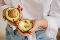 Close-up of a girl's hand holding an avocado cut in two - PhotoDune Item for Sale