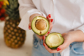 Close-up of a girl's hand holding an avocado cut in two - PhotoDune Item for Sale