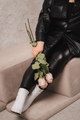 Close-up of legs and a bouquet of flowers of a stylish woman in black leather clothes sitting  - PhotoDune Item for Sale