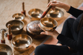 Close-up of a woman's hands sitting in a lotus position using a singing bowl indoors.  - PhotoDune Item for Sale
