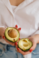 Close-up of a girl's hand holding an avocado cut in two - PhotoDune Item for Sale