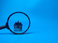 Miniature house and magnifying glass on blue background with copy space.Real estate concept. - PhotoDune Item for Sale