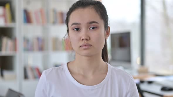 Portrait of Serious Young Asian Woman Looking at Camera 