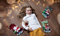 Smiling Child girl lying on floor at home and looking at camera. Christmas decor, lights bulb - PhotoDune Item for Sale