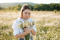 Attractive young adult woman pick up chamomile flowers in field - PhotoDune Item for Sale