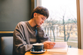Cute smiling teen boy reading book in cafe with cup of coffee - PhotoDune Item for Sale