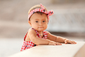 Lifestyle portrait of infant baby girl standing and holding on to a bench on 4th of July day - PhotoDune Item for Sale