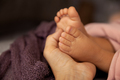 Tiny newborn baby feet in mother's hand at natural light in a selective focus - PhotoDune Item for Sale