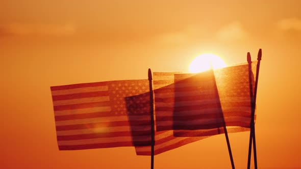 Several American Flags Against the Setting Sun and Orange Sky