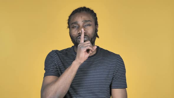 Casual African Man Gesturing Silence Finger on Lips Yellow Background