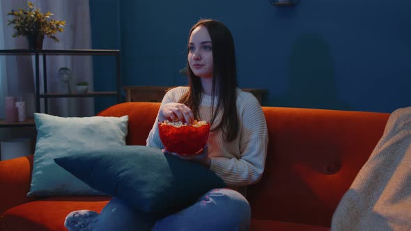 Woman Sitting on Sofa Alone Eating Popcorn and Watching Interesting Tv Serial Horror Film at Home