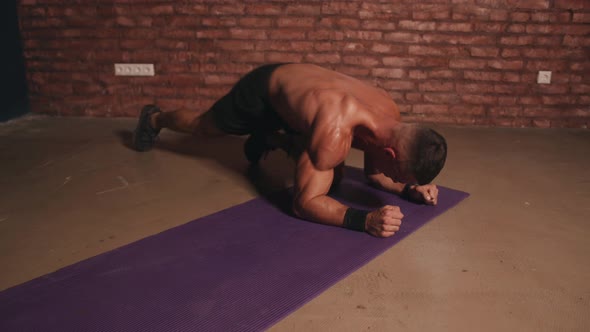 Young Muscular Man Doing Intense Training Indoors Without Equipment and Pumping Muscles in His Arms