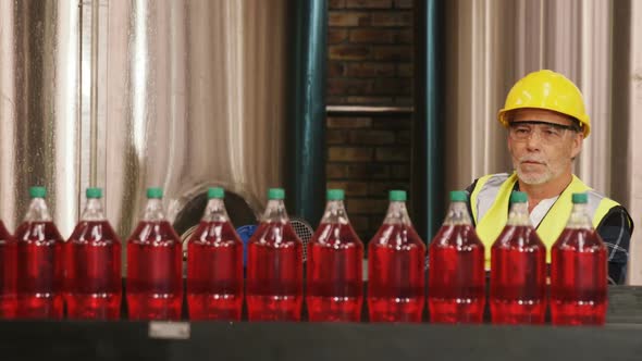 Worker checking juice bottles on production line