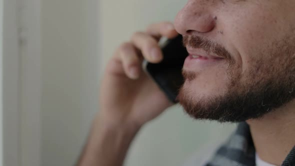 Close Up Shot of Smiling Young Bearded Man Talking on Smartphone.