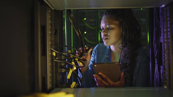 African american female computer technician using tablet working in business server room