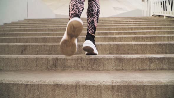 Close-up. The girl runs up the stairs . She is wearing black athletic sneakers and leggings