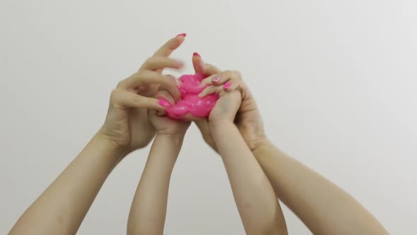 Woman and Child Hands Playing Oddly Pink Slime on White Background, Antistress
