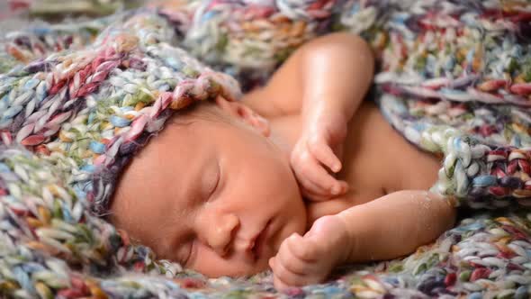 Newborn Baby Sleeps in a Knitted Scarf