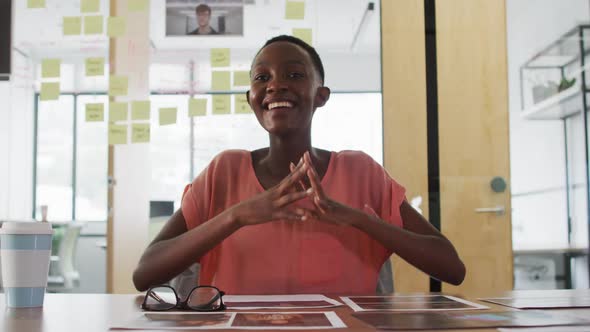 Smiling african american businesswoman at desk talking and gesturing during video call in office