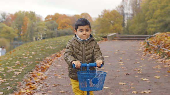 Cute Little Boy Riding on Kick Scooter in Autumn Park.