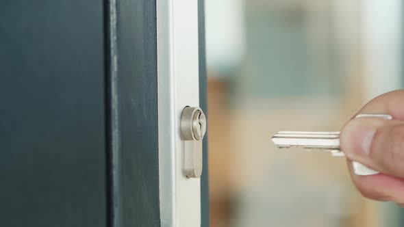 Man Slowly Inserts the Key Into the Keyhole of the Front Door